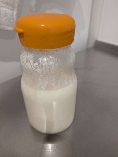 A glass bottle with an orange top containing Kefir