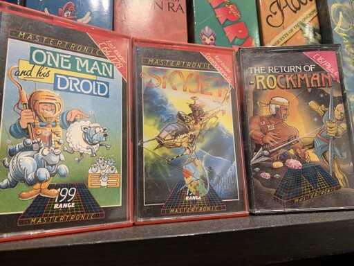 Three Mastertronic games on cassette tape sitting on my shelf. One Man Droid, Skyjet and the Return of Rockman. 